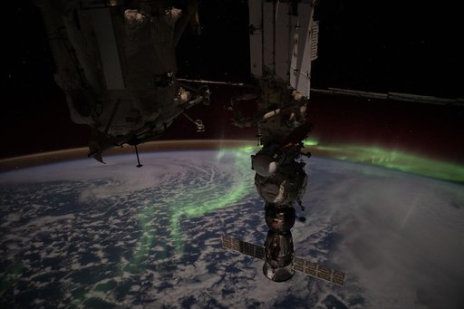The aurora australis streams above the Earth and into the atmospheric glow