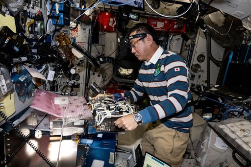 JAXA astronaut Kimiya Yui prepares new computer networking gear for installation