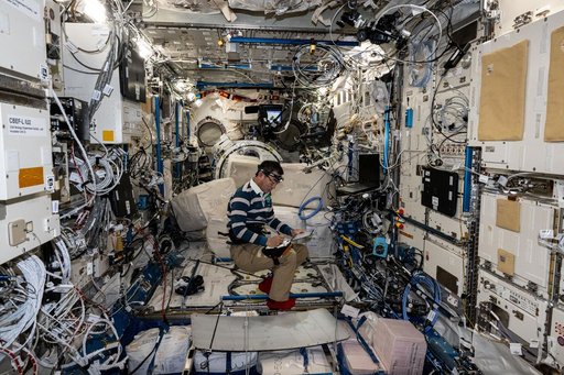 JAXA astronaut Kimiya Yui takes notes while installing new computer networking gear
