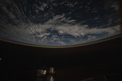 A faint airglow blankets Earth's horizon above the Pacific Ocean