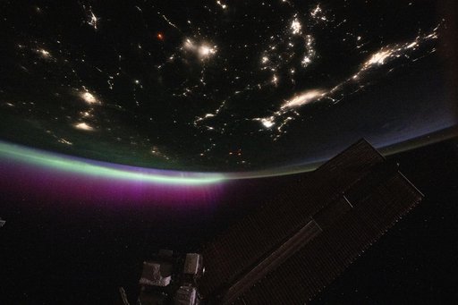 A diffuse aurora glows above Earth's horizon over Canada