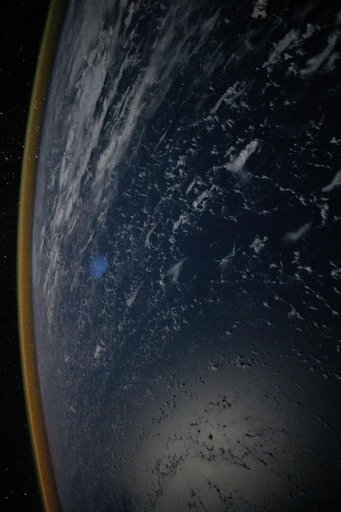 A red-yellow airglow blankets Earth's horizon above the Philippine Sea