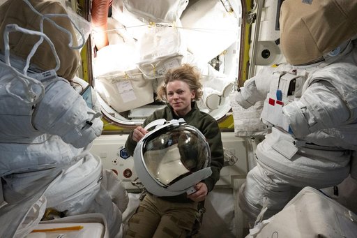 NASA astronaut Zena Cardman inspects a spacesuit helmet