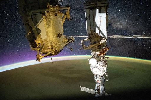 A yellow-green airglow blankets Earth as an orbital sunrise illuminates the planet