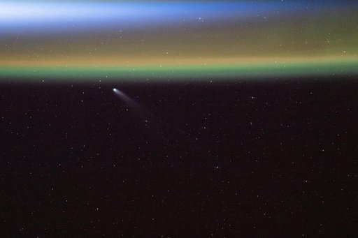 Comet Swan appears above Earth’s yellow-green airglow just before an orbital sunrise