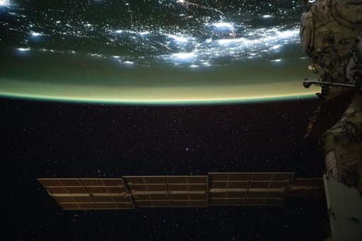 A yellow-green airglow blankets the city lights of North America