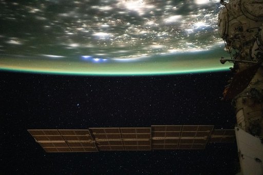 A blue-green airglow blankets the bright city lights of the eastern United States