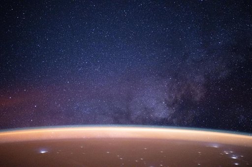 A reddish airglow blankets Earth beneath the Milky Way