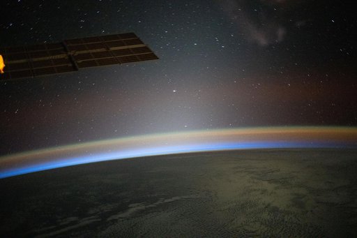 A red-yellow airglow blankets Earth as the last rays of an orbital sunset illuminate the atmosphere