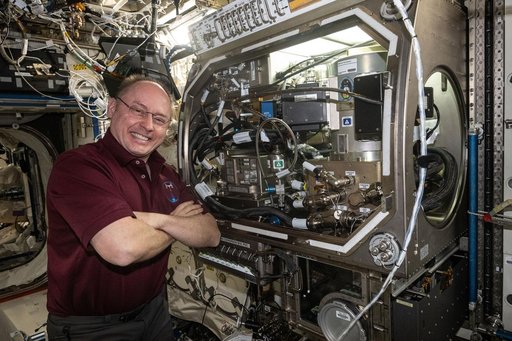 NASA astronaut Mike Fincke poses for a portrait next to the Microgravity Science Glovebox
