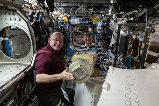 Astronauts Mike Fincke and Kimiya Yui work together to configure research hardware