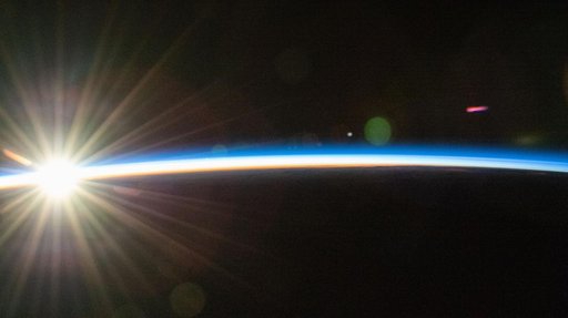 An orbital sunrise bursts above Earth's horizon