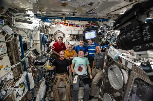 The seven-member Expedition 74 crew gathers for a portrait inside the International Space Station