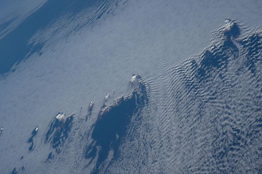 Snow-capped mountain tops of Alaska's Aleutian Islands pierce through the clouds