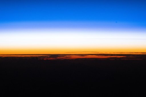 An orbital sunset silhouettes the cloud tops above the Pacific Ocean