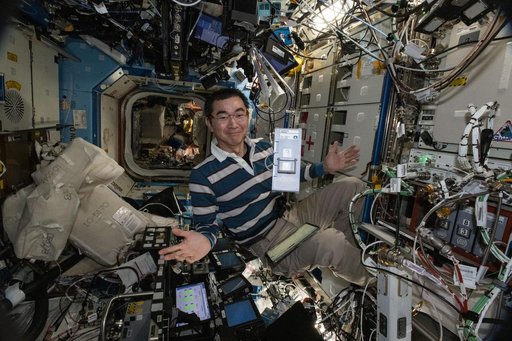 JAXA astronaut Kimiya Yui displays an advanced sample processing cassette