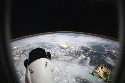 City lights sparkle across a cloudy Europe and the Alps