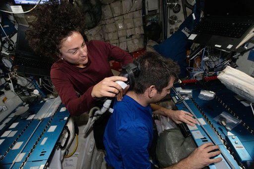 NASA astronaut Jessica Meir trims the hair of fellow NASA astronaut Jack Hathaway