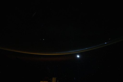 A dim airglow blankets Earth’s horizon as a faint Moon sets above the Indian Ocean