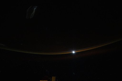 A dim airglow blankets Earth’s horizon as a faint Moon sets above the Indian Ocean