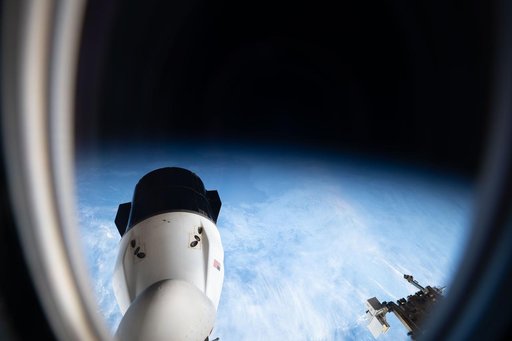 Peering out a window of a SpaceX Dragon spacecraft toward another Dragon spacecraft