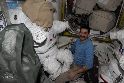 NASA astronaut Jack Hathaway works on a spacesuit inside the Quest airlock