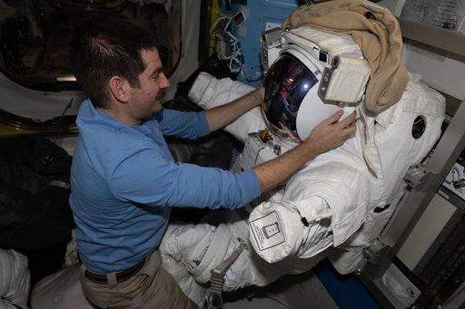 NASA astronaut Jack Hathaway works on a spacesuit inside the Quest airlock