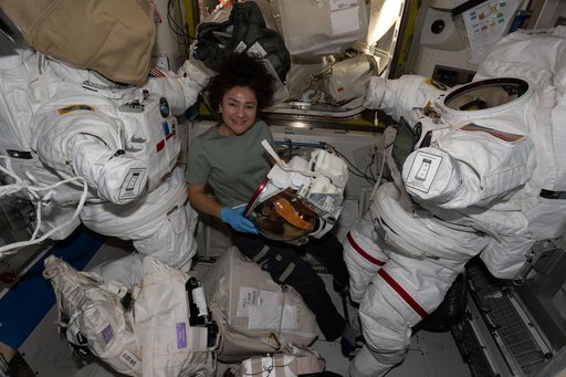 NASA astronaut Jessica Meir smiles for a portrait while preparing a helmet for installation