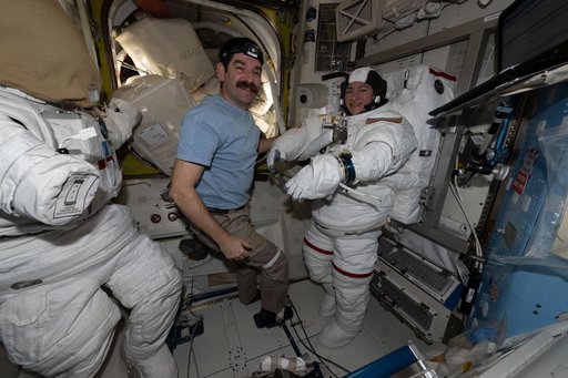 NASA astronaut Jack Hathaway assists NASA astronaut Jessica Meir as she tries on a spacesuit