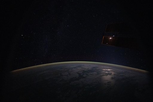 A yellow‑green airglow blanketing Earth’s atmosphere beneath a starry sky