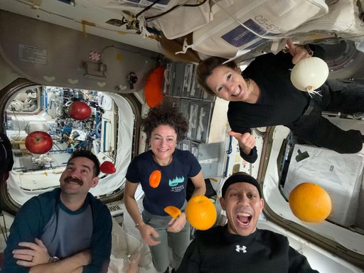 Expedition 74 flight engineers celebrate a shipment of fresh food aboard the International Space Station