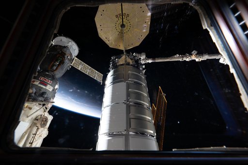 Two spacecraft attached to the International Space Station are seen through a window in the cupola