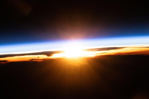 The last rays of an orbital sunset illuminate Earth's atmosphere and the cloud tops