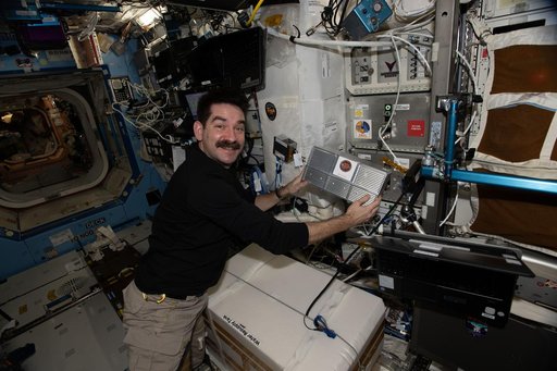 NASA astronaut Jack Hathaway installs research hardware inside a Powered Ascent Utility Locker