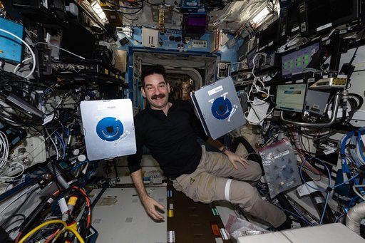 NASA astronaut Jack Hathaway shows off a pair of Advanced Space Experiment Sample Processor-4 research cassettes