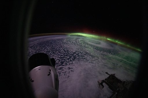 The aurora australis arcs above a swirling cloud formation over the Indian Ocean