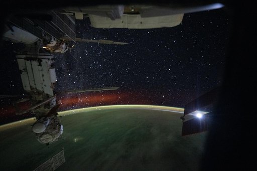 A bright atmospheric glow and a starry night sky above Earth