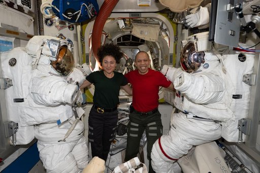 NASA astronauts Jessica Meir and Chris Williams pose with their spacesuits inside the Quest airlock