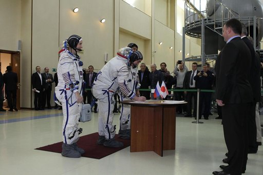 At the Gagarin Cosmonaut Training Center in Star City, Russia, Expedition 46-47 backup crewmember Anatoly Ivanishin of the Russian Federal Space Agency (Roscosmos) signs in Nov. 19 for the start of qualification exams as his crewmates, Kate Rubins of NASA (left) and Takuya Onishi of the Japan Aerosp