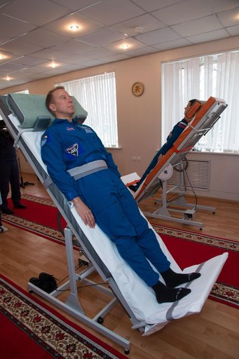 At the Cosmonaut Hotel crew quarters in Baikonur, Kazakhstan, Expedition 46-47 crewmember Tim Kopra of NASA took a turn on a tilt table to test his vestibular system Dec. 9 as part of his pre-launch training. Kopra, Tim Peake of the European Space Agency and Yuri Malenchenko of the Russian Federal S