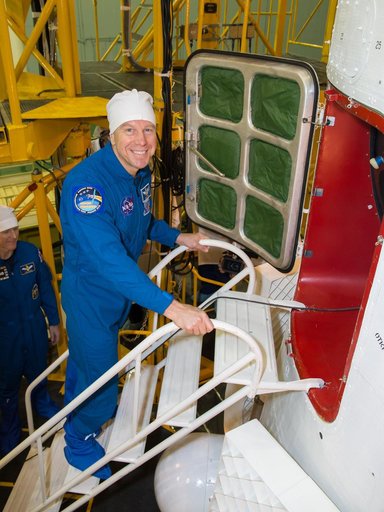 In the Integration Facility at the Baikonur Cosmodrome in Kazakhstan, Expedition 46-47 crewmember Tim Kopra of NASA flashes a smile before entering his Soyuz spacecraft Dec. 10 during a final fit check and inspection. Kopra, Tim Peake of the European Space Agency and Yuri Malenchenko of the Russian 