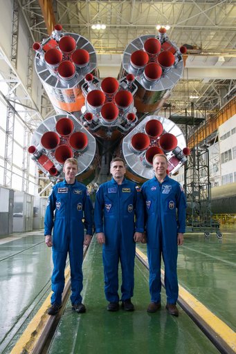 In the Integration Facility at the Baikonur Cosmodrome in Kazakhstan, Expedition 46-47 crewmembers Tim Peake of the European Space Agency (left), Yuri Malenchenko of the Russian Federal Space Agency (Roscosmos, center) and Tim Kopra of NASA (right) posed for pictures Dec. 10 in front of the first st