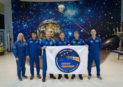 During a break from training, the Expedition 46-47 prime and backup crewmembers toured the Korolev Museum at the Baikonur Cosmodrome in Kazakhstan Dec. 10 and displayed a flag bearing the logo for the prime crew���s Soyuz mission. From left to right are backup crewmembers Kate Rubins of NASA and Tak