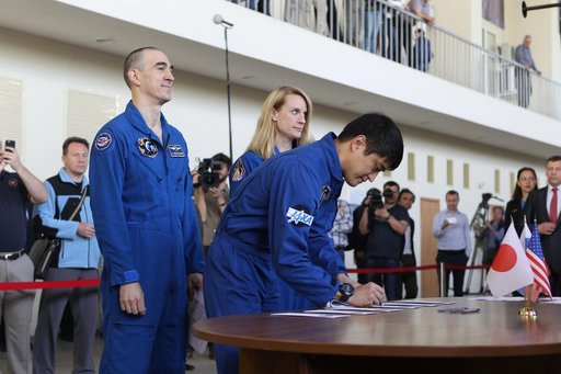 At the Gagarin Cosmonaut Training Center in Star City, Russia, Expedition 48-49 prime crewmember Takuya Onishi of the Japan Aerospace Exploration Agency signs in for the start of final qualification exams May 26 as his crewmates, Anatoly Ivanishin of Roscosmos (left) and Kate Rubins of NASA (right) 
