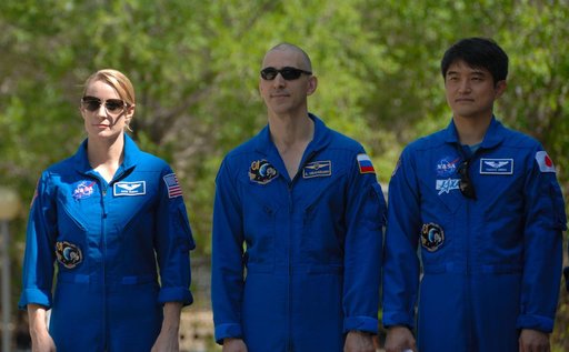 Outside their Cosmonaut Hotel crew quarters in Baikonur, Kazakhstan, Expedition 48-49 crewmembers Kate Rubins of NASA (left), Anatoly Ivanishin of Roscosmos (center) and Takuya Onishi of the Japan Aerospace Exploration Agency (right) listen to remarks June 26 during the traditional raising of the Am