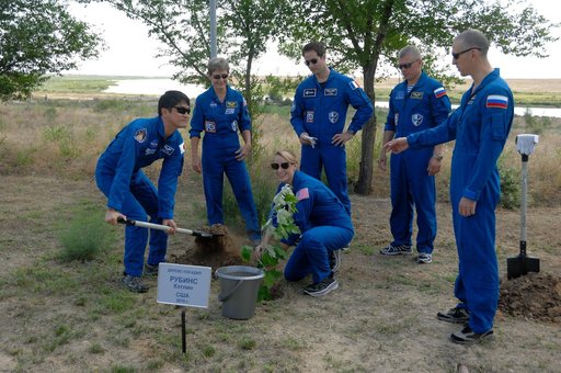 At the Cosmonaut Hotel in Baikonur, Kazakhstan, Expedition 48-49 crewmember Takuya Onishi of the Japan Aerospace Exploration Agency (left) lends a hand to NASA���s Kate Rubins (crouching) as she plants a tree in her name June 30 in traditional pre-launch activities. Standing from left to right are b