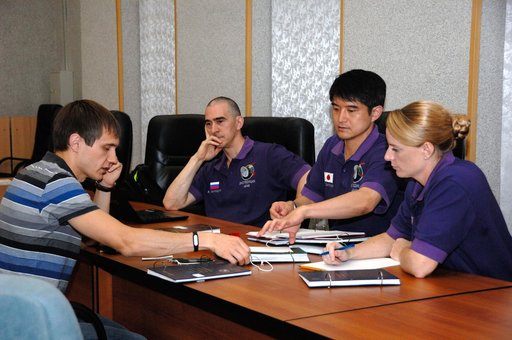 At the Cosmonaut Hotel in Baikonur, Kazakhstan, Expedition 48-49 crewmembers Anatoly Ivanishin of Roscosmos (second from left), Takuya Onishi of the Japan Aerospace Exploration Agency (second from right) and Kate Rubins of NASA (far right) listen to a rendezvous instructor June 30 during pre-launch 