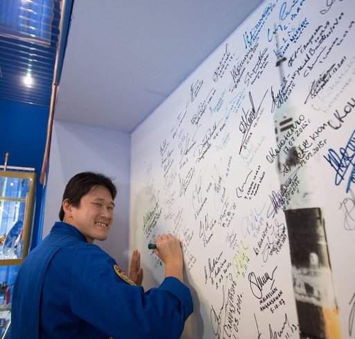 jsc2017e138116 - At the Korolev Museum at the Baikonur Cosmodrome in Kazakhstan, Expedition 54-55 prime crewmember Norishige Kanai of the Japan Aerospace Exploration Agency (JAXA) signs a wall mural Dec. 13 as part of traditional pre-launch ceremonies. Ka