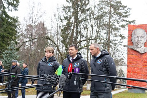 jsc2018e097267 - With the statue of Vladimir Lenin serving as a backdrop, Expedition 58 crewmembers Anne McClain of NASA (left), Oleg Kononenko of Roscosmos (center) and David Saint-Jacques of the Canadian Space Agency (right) answer reporters’ question