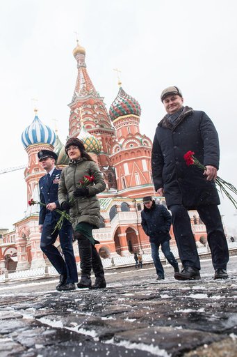 jsc2019e004432 - With St. Basilâ€™s Cathedral in Red Square in Moscow providing a wintry backdrop, Expedition 59 crewmembers Nick Hague of NASA (left), Christina Koch of NASA (center) and Alexey Ovchinin of Roscosmos (right) walk toward the Kremlin Wall F